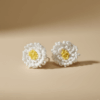 Handmade white crochet flower earrings with yellow beaded center placed on soft beige background.